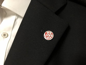 「WE LOVE とよた」ロゴマークのピンバッジをスーツにつけた様子