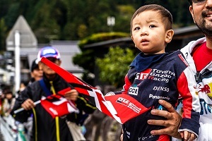 沿道で応援手旗を振る子ども