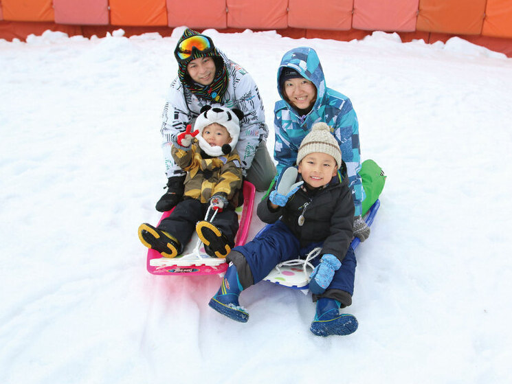 雪そりゲレンデで遊ぶ親子