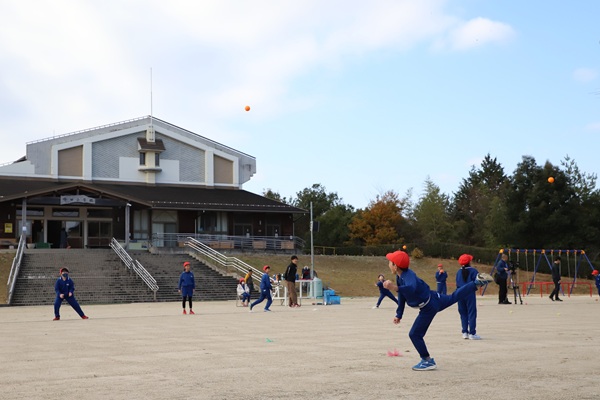 写真説明：講師の指導でボール投げに取り組む児童たち