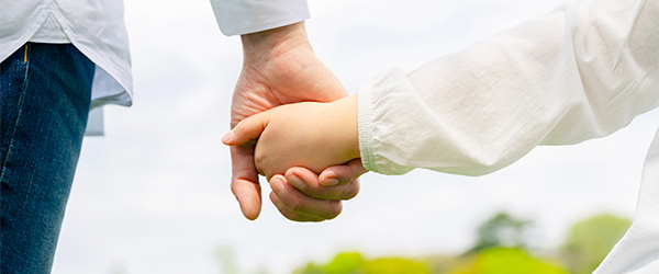 写真：手をつなぐ大人と子ども