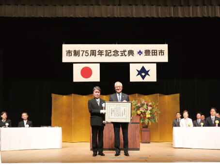 壇上で記念撮影をする市政功労者の三宅英臣氏と太田市長